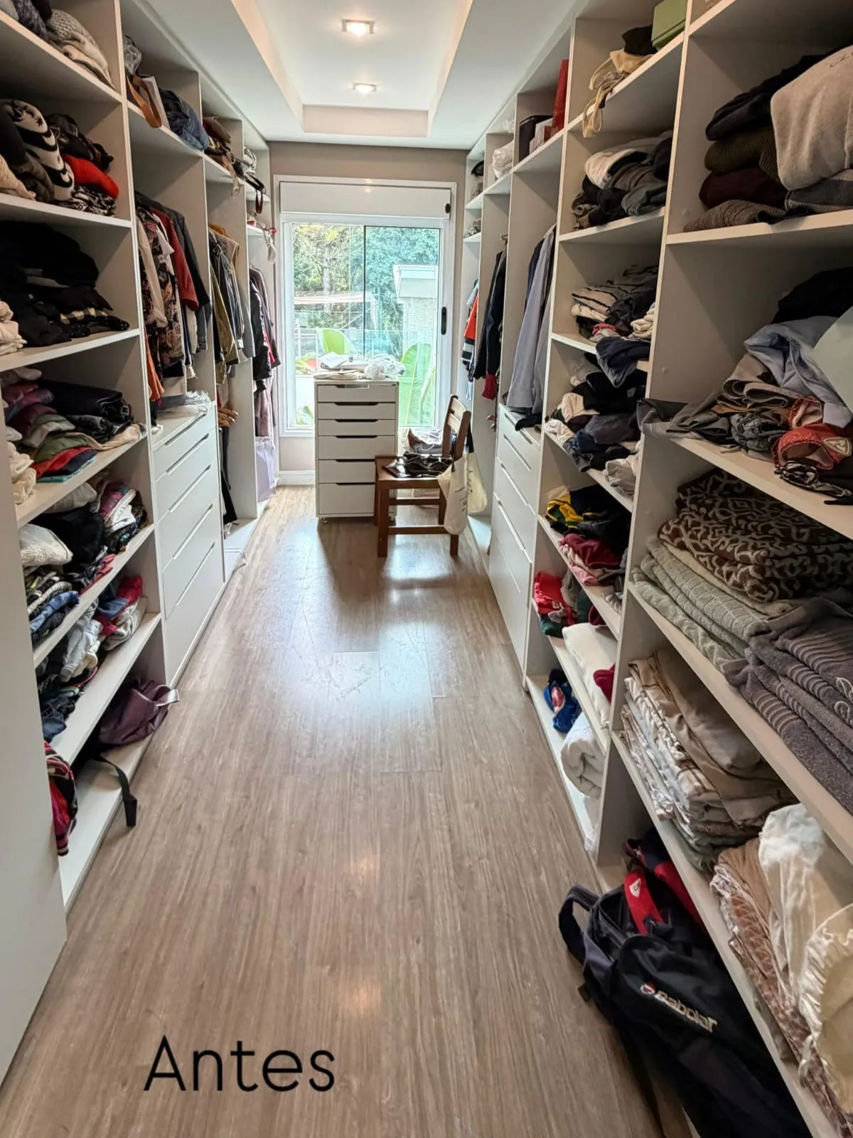 Closet corredor com prateleiras lotadas, roupas empilhadas e mochilas no chão