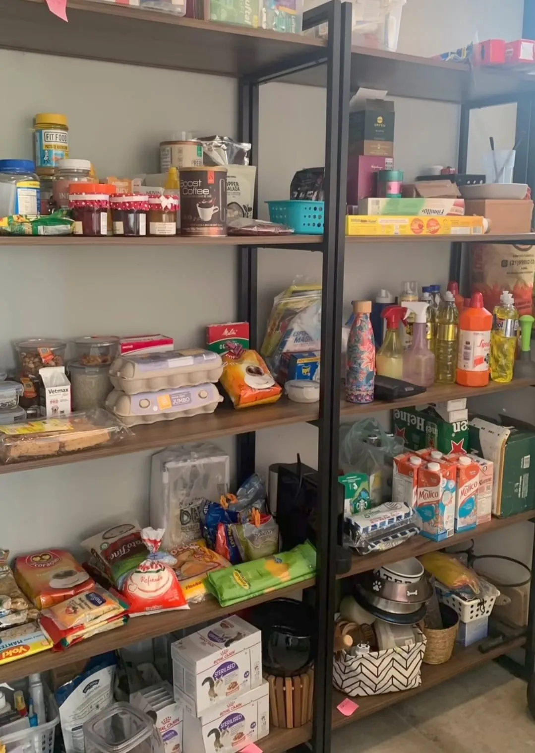 Despensa com alimentos, produtos de limpeza e caixas misturados nas prateleiras